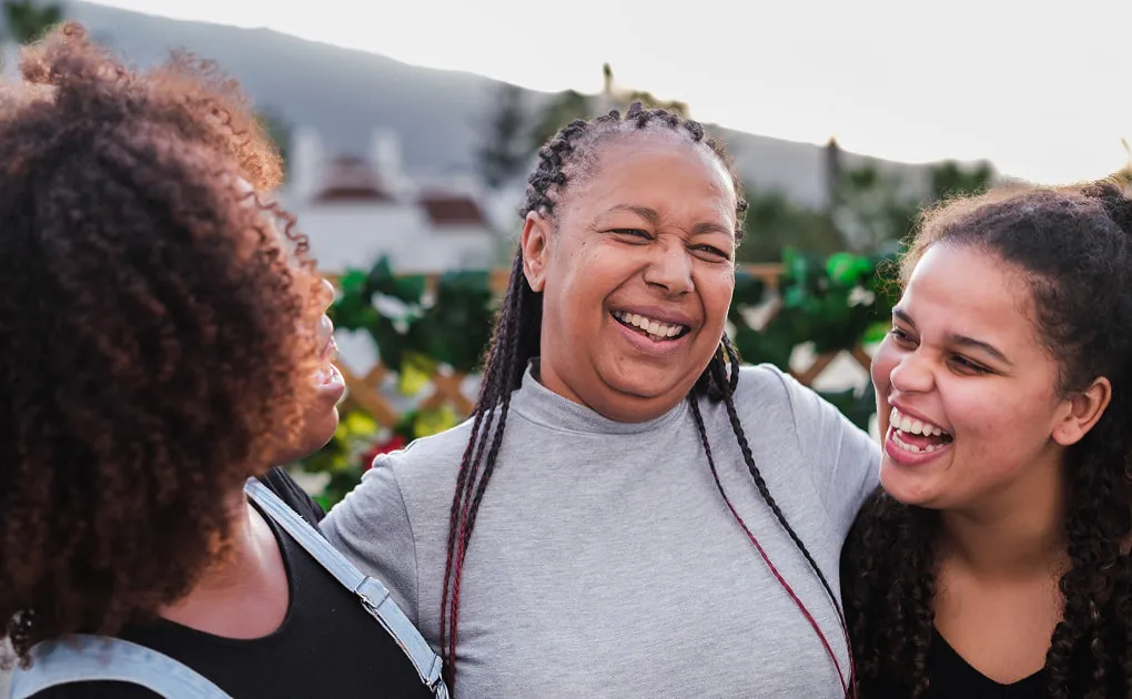 Three generations of women laughing together outdoors